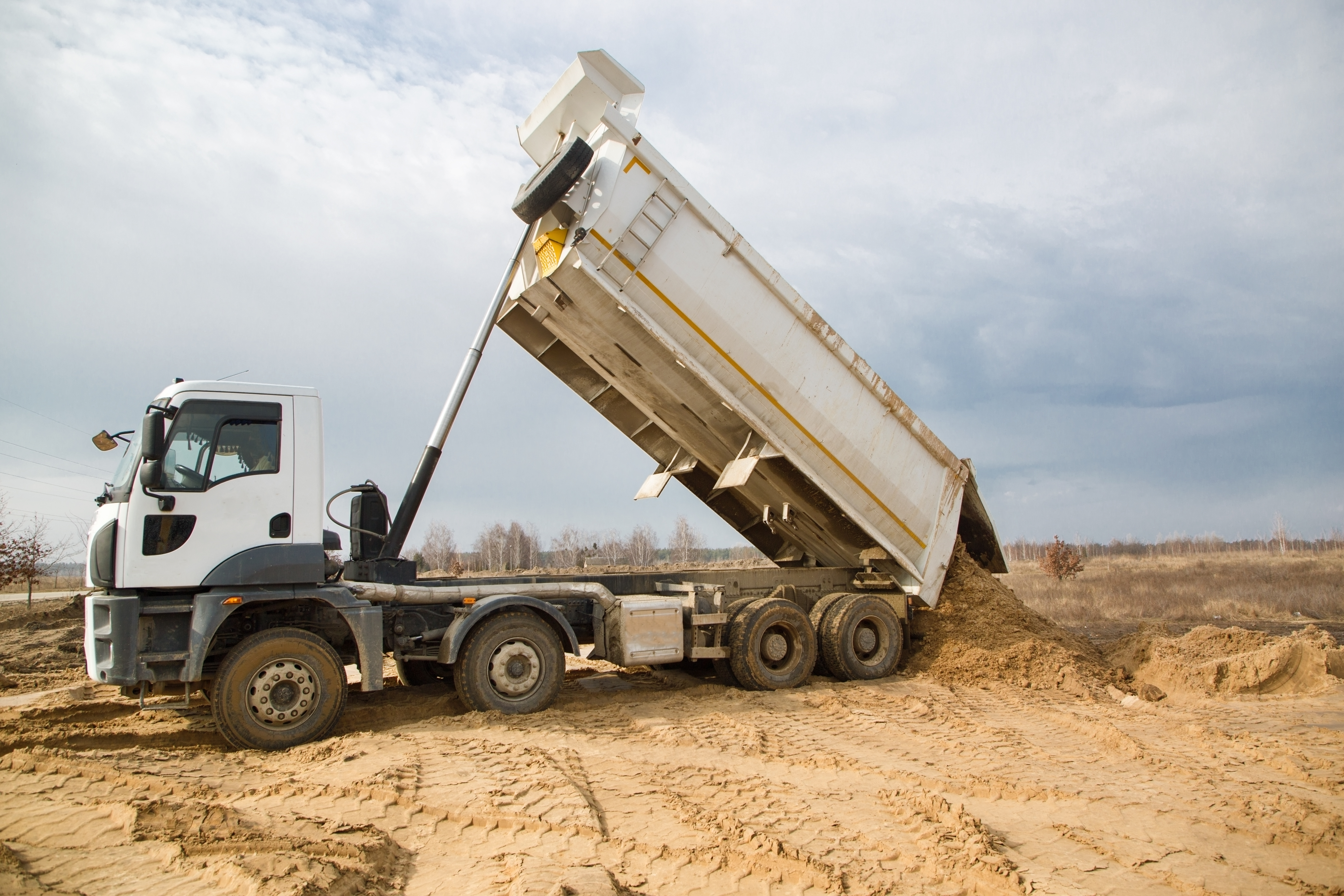 dump truck with a raised body at a construction site in the process of unloading soil